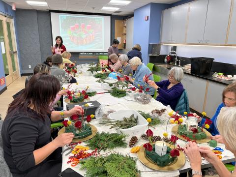 A group of patrons sitting at a table assembling flower arrangements.