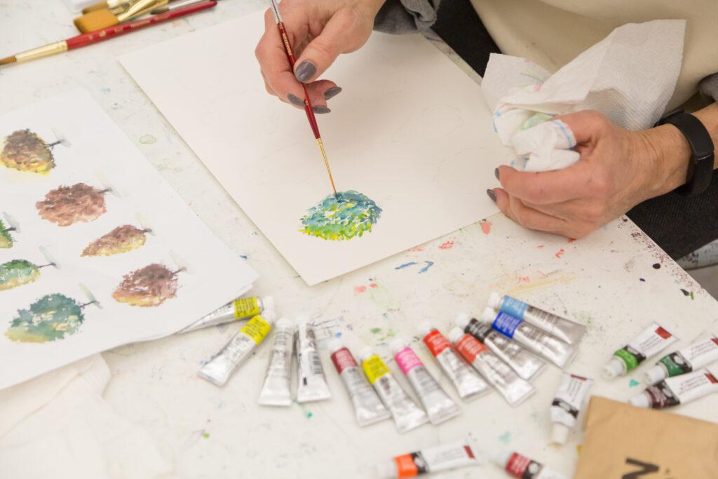 Close up of someone's hand using brush to paint watercolors